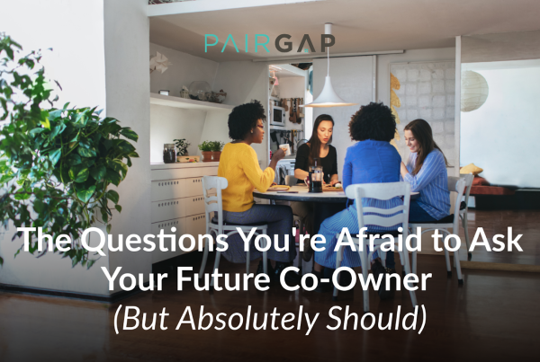 Four friends sitting around a dining table having a conversation about co-buying a home together.