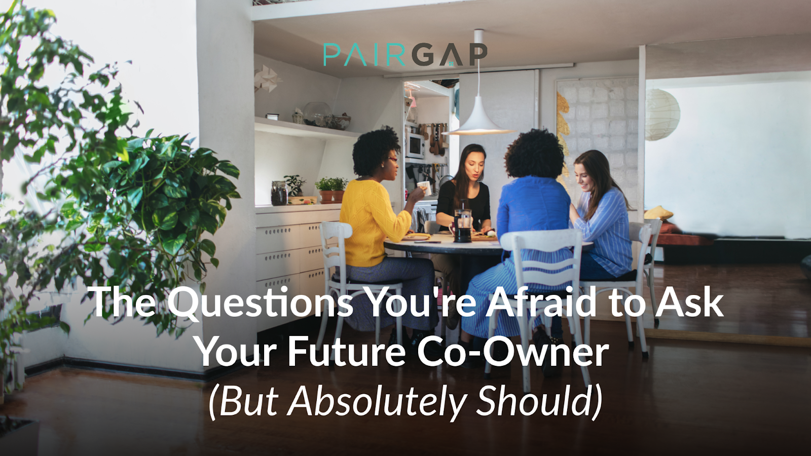 Four friends sitting around a dining table having a conversation about co-buying a home together.
