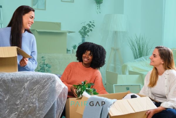 Three friends unpacking boxes together after deciding to co-buy their first home through shared homeownership