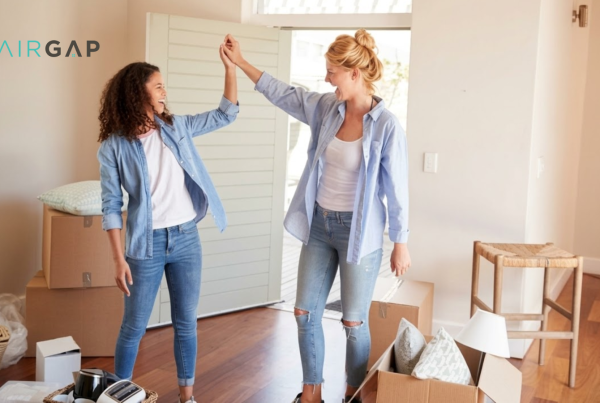 Two women celebrating in their new home surrounded by moving boxes, high-fiving after completing a co-buying purchase together.
