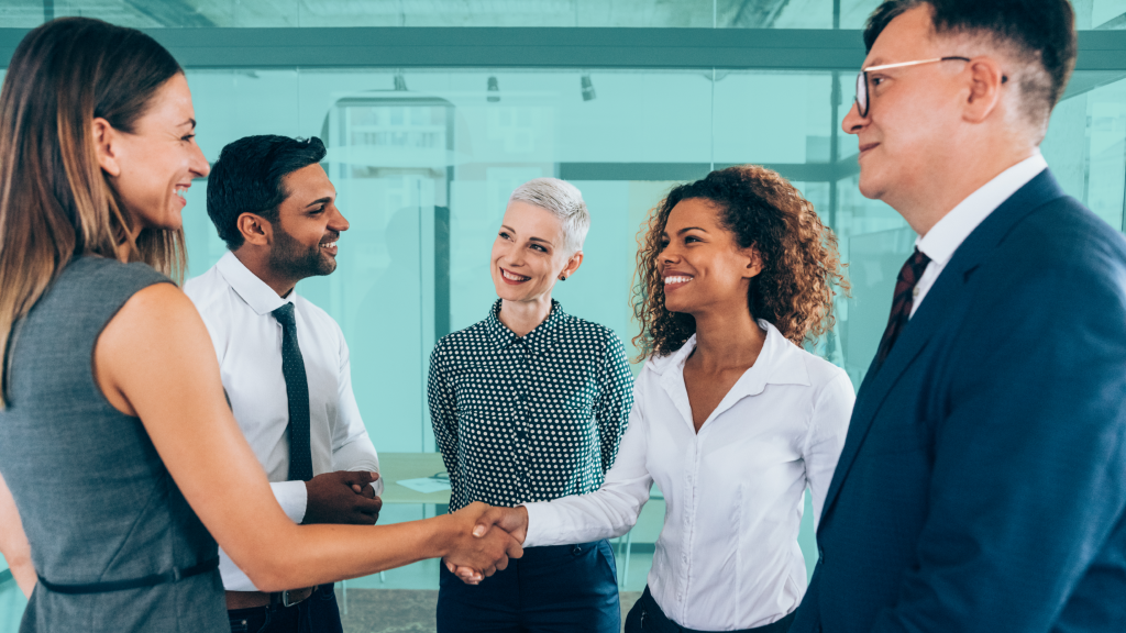 Diverse group of professionals shaking hands in a modern office, representing real estate co-buying partnerships and shared investment agreements.