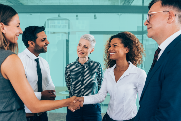 Diverse group of professionals shaking hands in a modern office, representing real estate co-buying partnerships and shared investment agreements.