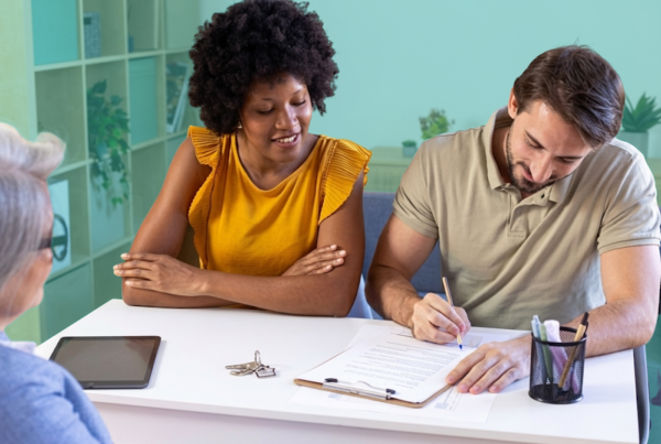 An unmarried couple signing a property agreement with a real estate advisor, house keys visible on the table, representing co-ownership documentation for co-buyers.