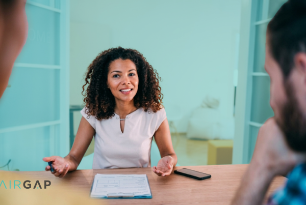 A real estate advisor explaining co-ownership terms to two clients across a table, with a document and the Pairgap logo visible, representing the Real Estate Prenup Builder.