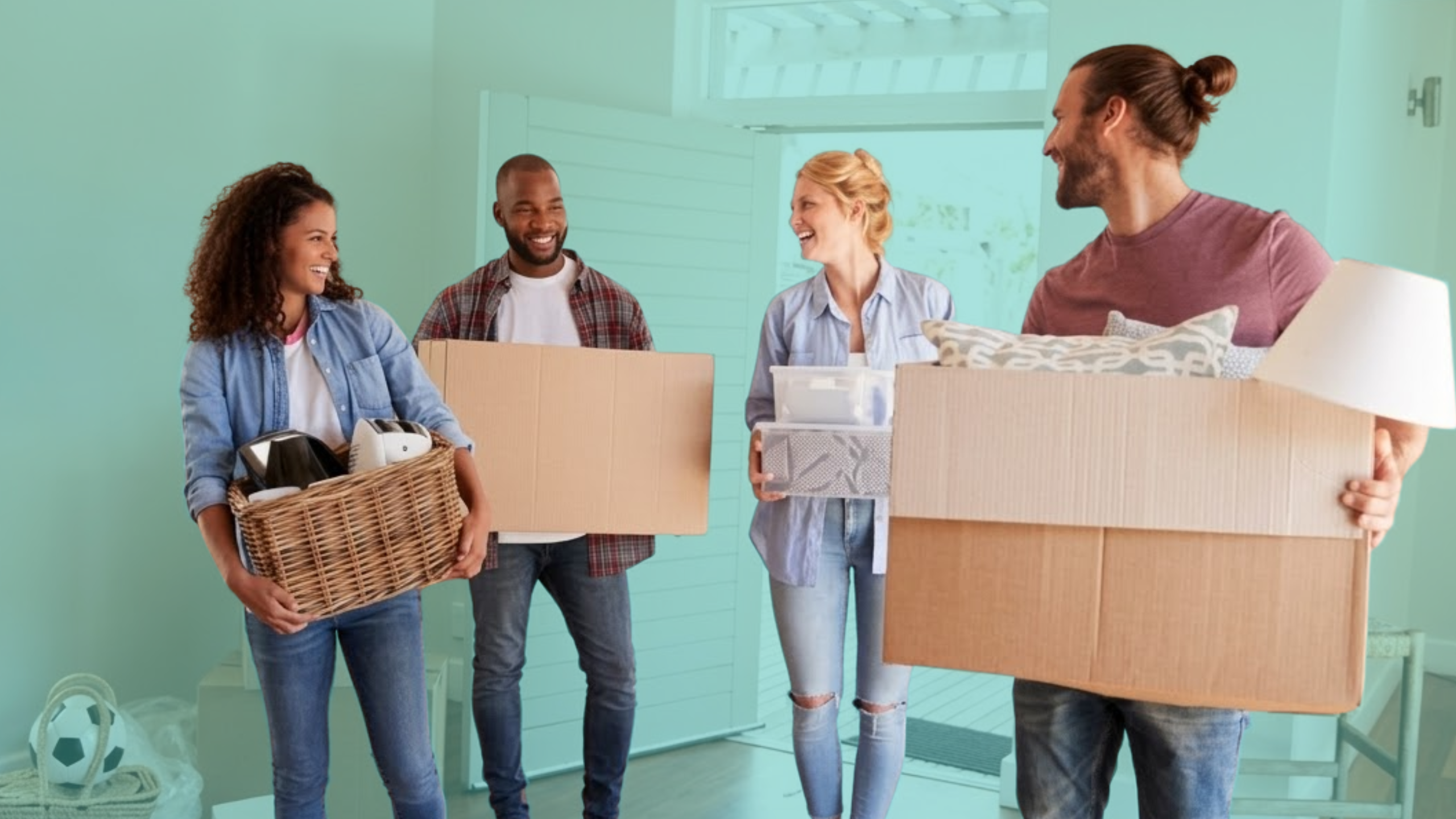 Group of first-time homebuyers carrying moving boxes into a new home, representing shared homeownership and co-buying with friends.