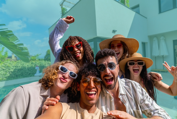 Group of friends standing outside a home, celebrating and preparing to co-buy property together during the summer home buying season.