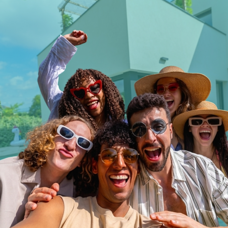 Group of friends standing outside a home, celebrating and preparing to co-buy property together during the summer home buying season.