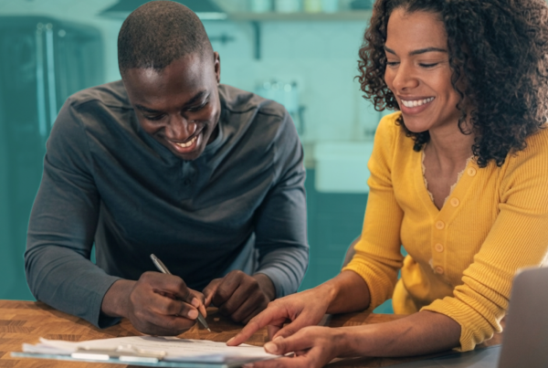 Friends reviewing homeownership documents and discussing a co-buying agreement before purchasing a home together.