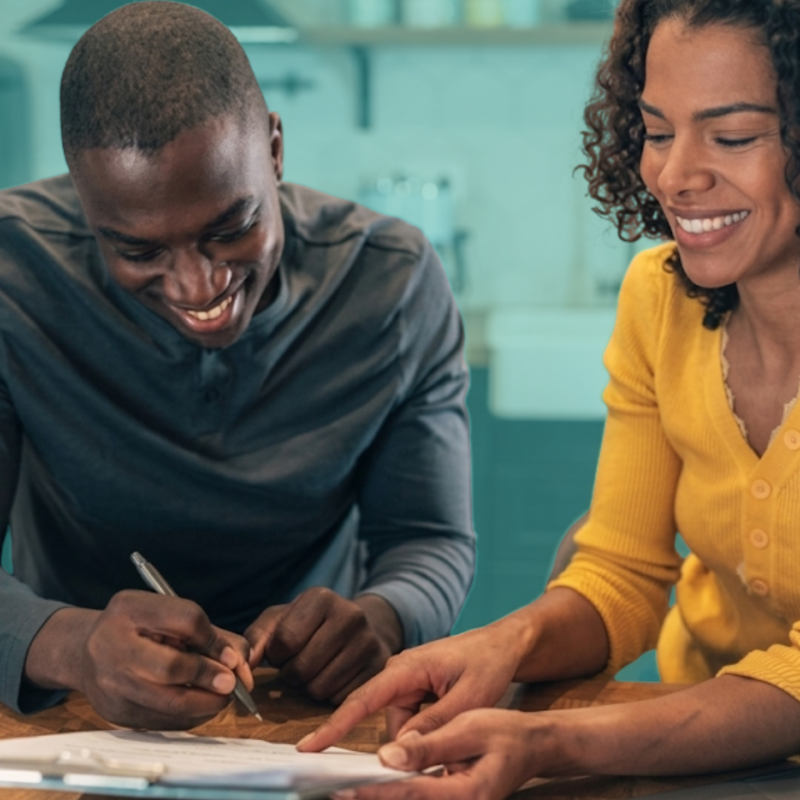 Friends reviewing homeownership documents and discussing a co-buying agreement before purchasing a home together.