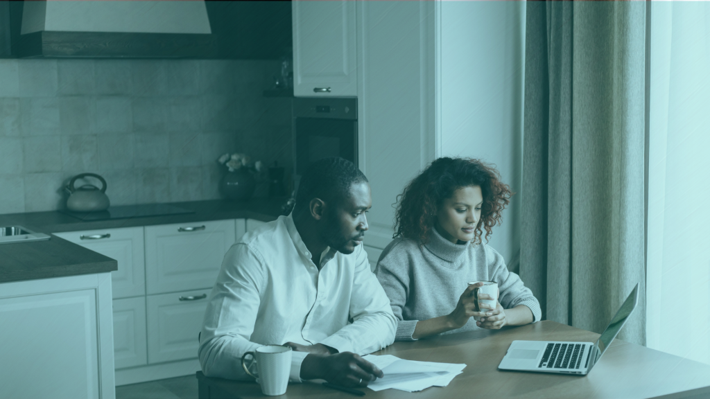 Two co-buyers sitting at a kitchen table reviewing a co-ownership agreement together