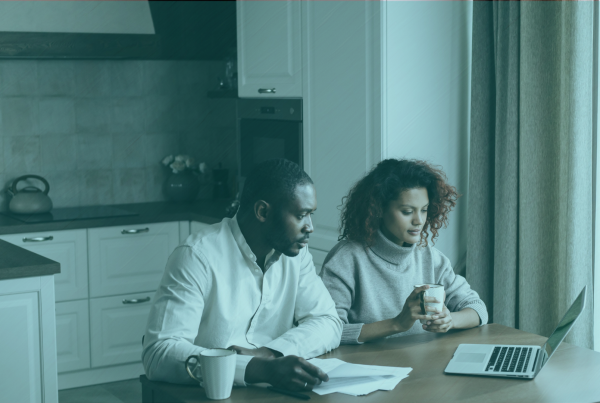 Two co-buyers sitting at a kitchen table reviewing a co-ownership agreement together