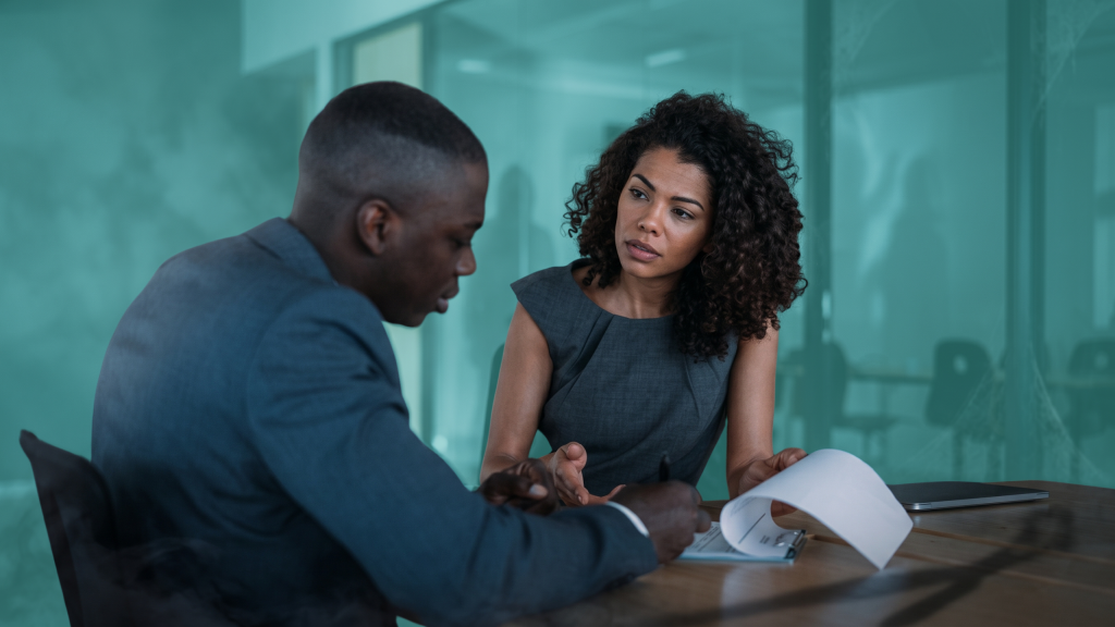 Two co-buyers reviewing paperwork together while discussing a house prenup agreement